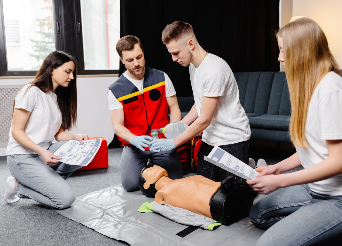 CPR training session with instructor demonstrating on a dummy and participants watching attentively